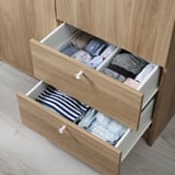 Open wooden drawer organizer with folded clothes, showcasing efficient storage solution.