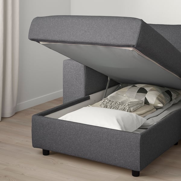 A gray VIMLE sofa-bed with open storage compartment, revealing pillows and a blanket inside.