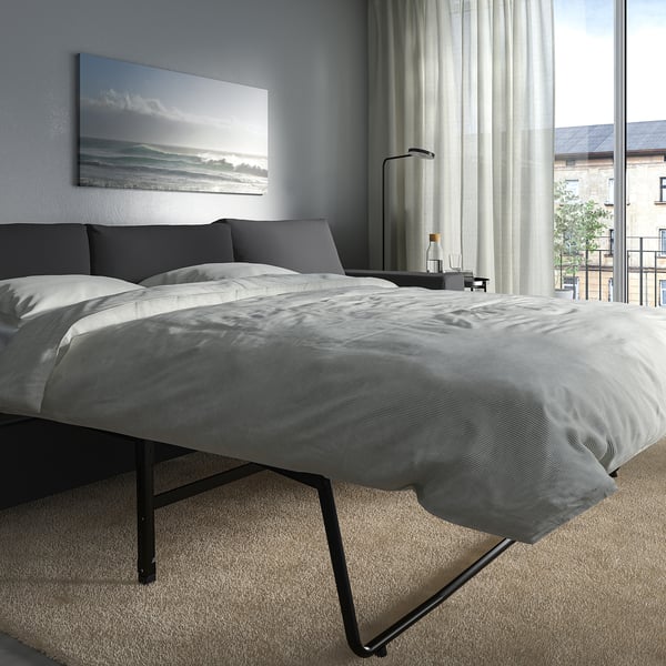 Modern bedroom with VIMLE sofa-bed, thick mattress, ocean art, and lamp.
