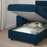 Blue sofa with lift-up storage compartment, showing neatly folded white blanket inside.