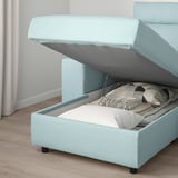 Light blue sofa with storage under seat, open to show blankets and pillows.
