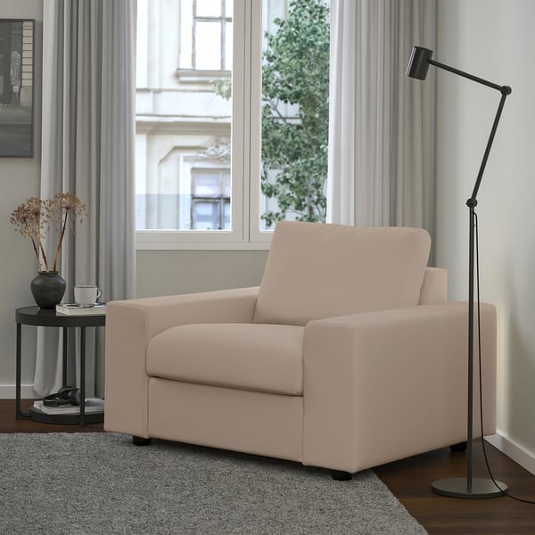 Beige VIMLE armchair between crate table and tall lamp, with a large window, stylish decor, and inviting ambiance.
