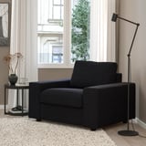 Modern living room with black VIMLE sofa, lamp, flowers, rug.