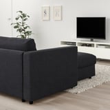Modern living room with grey VIMLE sectional sofa, tv, plant, rug, abstract art, natural light.