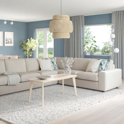 Modern living room with large beige VIMLE sectional sofa, light wood coffee table, and large window with blue drapes.