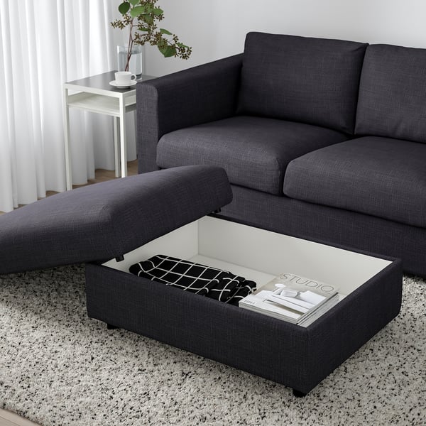 Modern grey sofa with lift-top ottoman, hidden storage, and magazine.