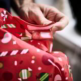 Child holding festive apron with pocket, perfect for kitchen fun.