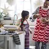 Two people, a man and a girl, wear aprons and bake in a cozy kitchen, with the girl using cookie cutters on dough.