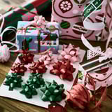 Assorted colorful gift bows in various sizes, red and green, displayed on white paper, ready for gift wrapping.