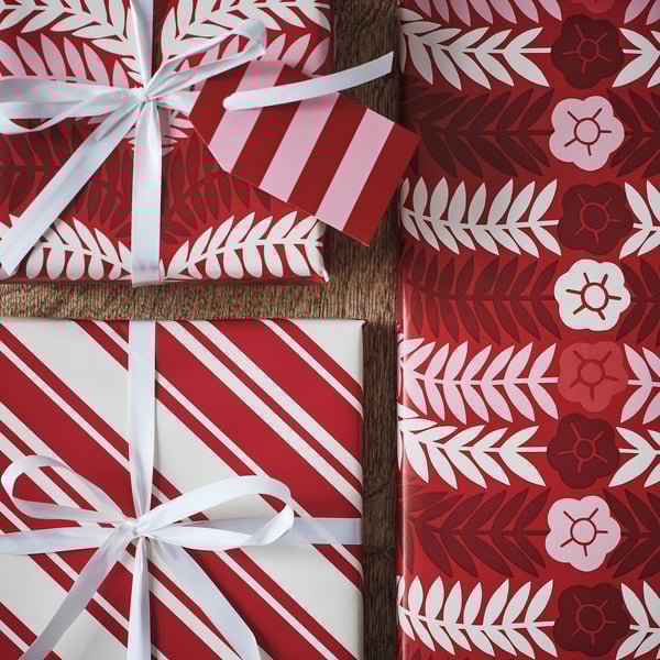 Three vibrant red gift boxes wrapped in festive, patterned paper tied with elegant white ribbons.