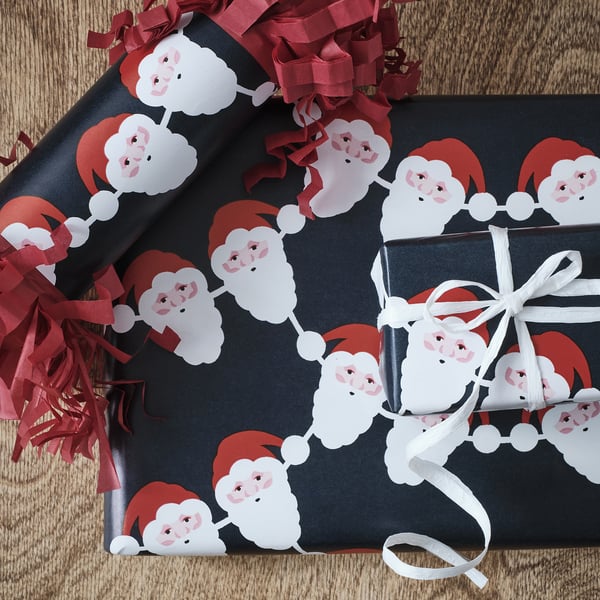 Black wrapping paper featuring repeating santa faces, tied with white ribbon and red curled decorations.
