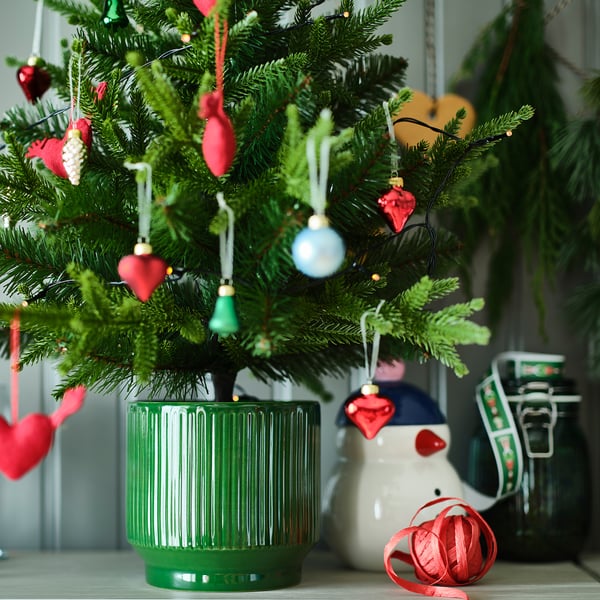 VINTERFINT green pottery planter, smaller than snowman, holds mini tree with colorful ornaments.