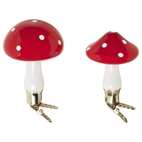 Two shiny red mushroom-shaped christmas decorations with white spots and gold clips for hanging.
