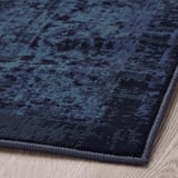 Vintage blue rug on floor, corner shown, low pile, no shedding, durable, worn pattern.