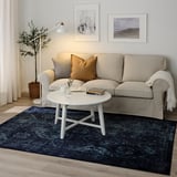 Beige sofa with brown pillow on VONSBÄK rug, vintage, dark blue pattern.