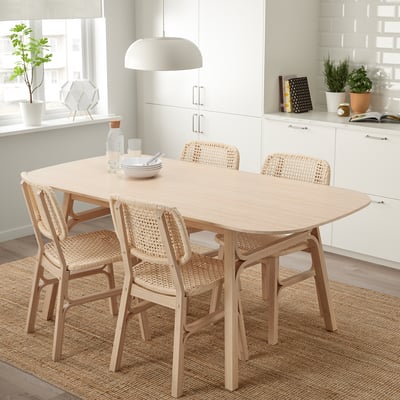 A VOXLÖV dining set with a light brown bamboo wooden table and matching chairs featuring woven seats and backs.