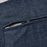 Dark blue textured fabric sofa with a smooth black zipper partially opened, revealing inner lining.