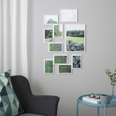 Wall with various nature photo frames, grey armchair, blue side table, modern decor.