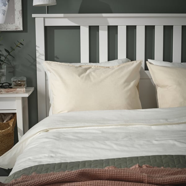 Beige ÄNGSLILJA Kissenbezüge aus Baumwolle auf dem Bett mit weißem Kopfteil, Bettdecke, brauner Überwurf.