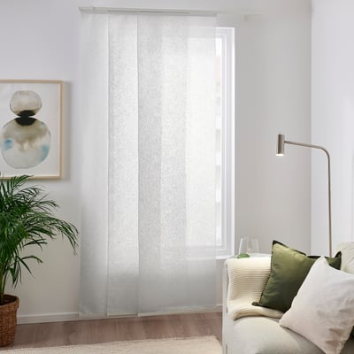 Weiße AMPELSÄV-Vorhänge mit Blattmuster hängen in der Nähe von Fenster und Couch und dämpfen das Licht. Pflanzen und Wandkunst sorgen für beruhigende Grüntöne.
