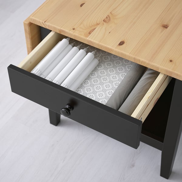 Offene Couchtischschublade aus Holz mit Kerzen. Schwarze Henkel und gemustertes Innenfutter.