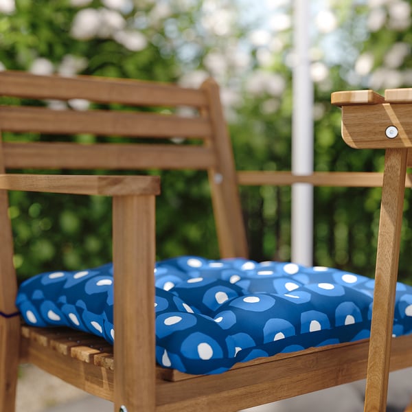 Brauner Outdoor-Stuhl aus Holz mit blau-weißem Punktkissen.