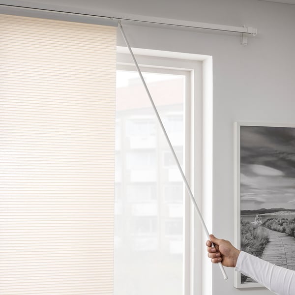 Eine Person zeichnet einen durchsichtigen Paneelvorhang über ein großes Fenster, das die Privatsphäre erhöht und gleichzeitig natürliches Licht in einen minimalistischen Raum lässt.