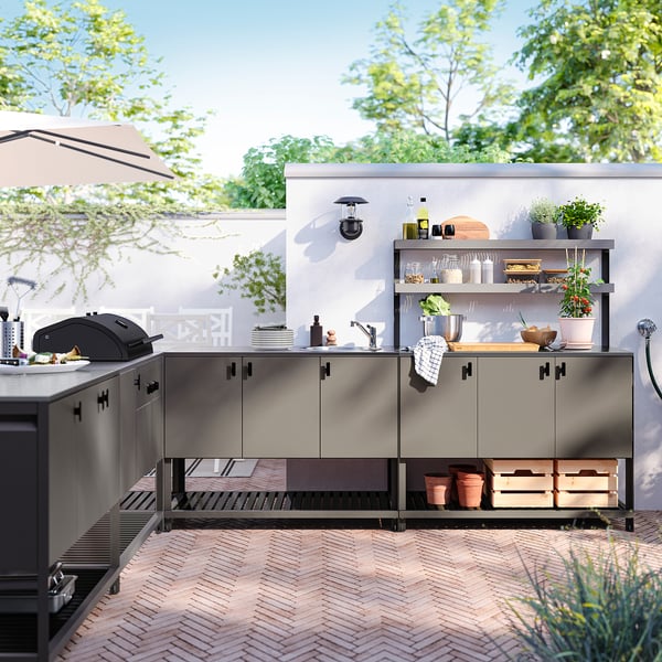 Moderne Außenküche mit BÅTSKÄR-Schränken mit Stahldesign, Theke, Grill, Spüle, Regalen und grüner Umrandung.