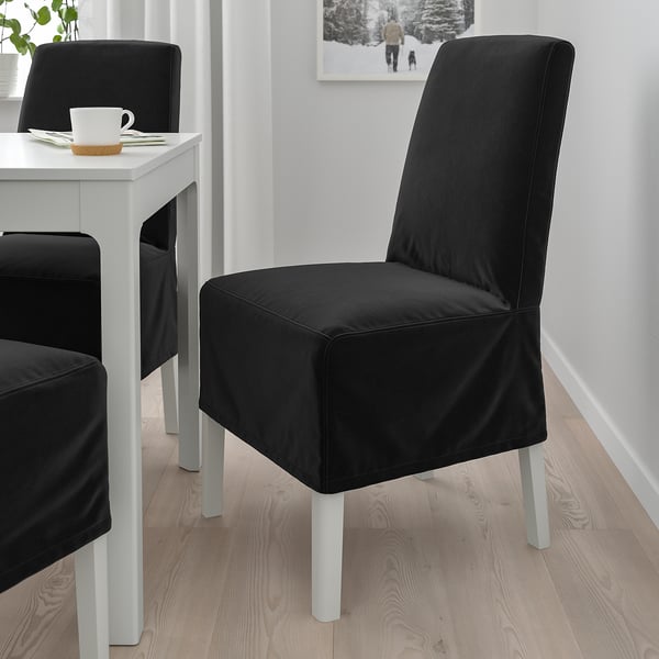 Zwei große schwarze BERGMUND Stühle mit Metallbeinen neben kleinem weißen Tisch mit Kaffeetasse.