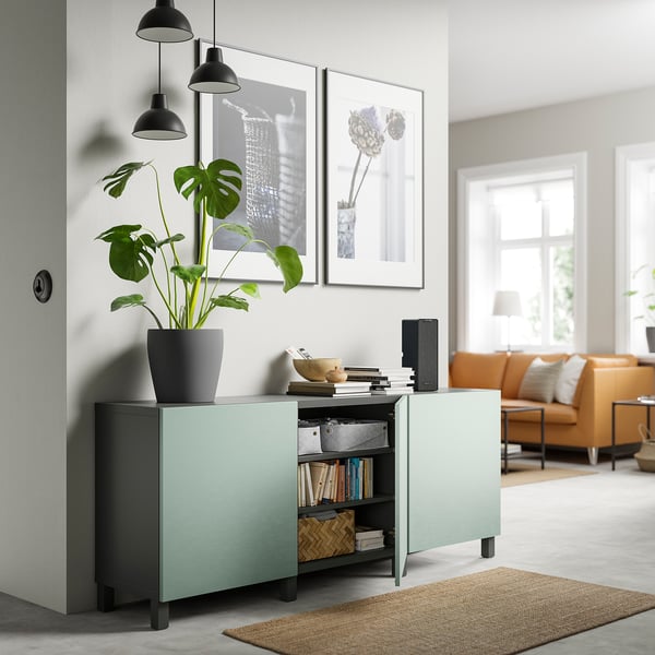 Modernes Wohnzimmer mit hellblauem BESTÅ-Stauraum, schwarzen Pendelleuchten, orangefarbenem Sofa und großen Fenstern.