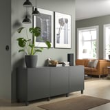 Moderner Wohnraum mit grauem BESTÅ-Stauraum, grünen Wänden, orangefarbener Couch und Hängepflanzen.