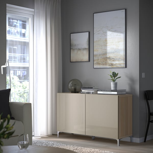 Modernes, minimalistisches Wohnzimmer mit BESTÅ-Stauraum, hellem Holz und Beige, mit abstrakter Kunst, Topfpflanze und Glas.