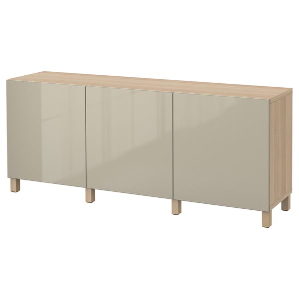Ein cremefarbenes BESTÅ Sideboard mit drei Türen und Holzbeinen aus Spanplatten und massiver Eiche.