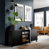 Modernes Zimmer mit dunkelgrauen Wänden, BESTÅ Sideboard, Pflanze, Büchern, Lautsprecher und beleuchteten Kunstwerken.