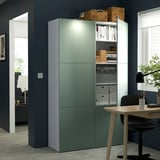 Modernes Büro mit grünem BESTÅ-Stauraum, verstellbaren Regalen und integrierten Leuchten. Bietet Platz für Bücher und Zubehör, gepaart mit einem Schreibtisch und Stuhl aus Holz.