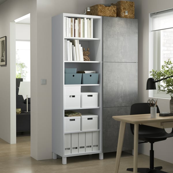Weißer BESTÅ-Stauraum im Home Office mit gemischten offenen/geschlossenen Regalen, Schreibtisch und Stuhl in der Nähe. Helles Zimmer mit Holzboden.