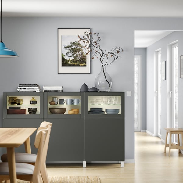 Modernes Esszimmer mit BESTÅ-Schrank, Tisch und Stühlen. Pendelleuchte, gerahmtes Foto und Vasendekor.