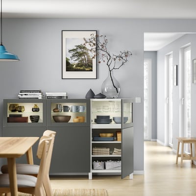 Moderner Essbereich mit grauem BESTÅ-Stauraum, Holztisch, Stühlen und Dekorationsartikeln.