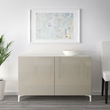 Minimalistisches Wohnzimmer mit einem BESTÅ Sideboard mit reflektierender Oberfläche und weißer Schale, begleitet von einem gerahmten Collagedruck.