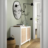 Weißes BESTÅ Sideboard mit geflochtenen Türen, Spiegel und Dekor in grünem Eingang.