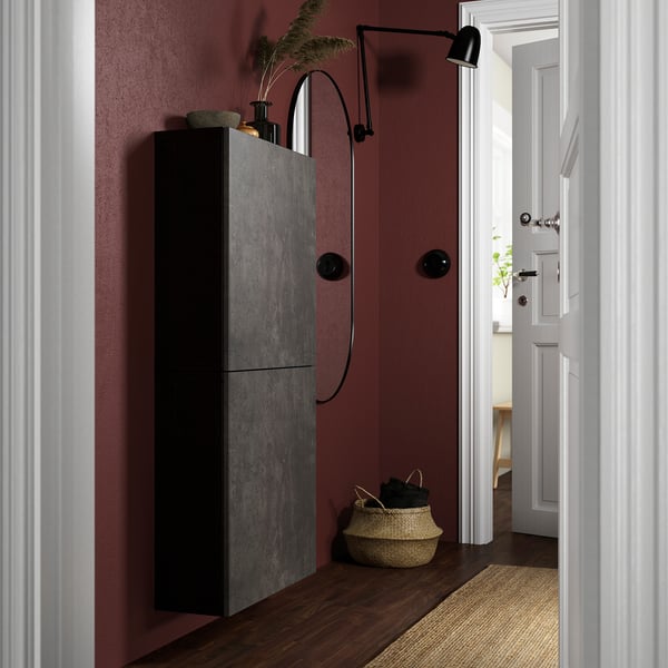 Moderner Eingangsbereich mit dunkelroter Wand, hohem schwarzen BESTÅ-Schrank, geflochtenem Korb und Wandlampe.