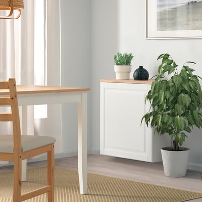 Minimalistischer Essbereich mit BESTÅ Sideboard, Pflanze und passendem Tisch/Stühlen, sanftes Licht aus dem Fenster.