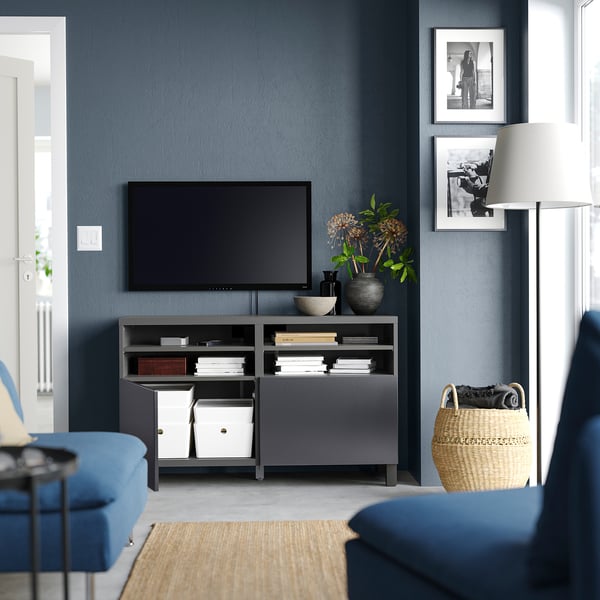 Wohnzimmer mit blauen Wänden, BESTÅ TV-Bank, Couch, Teppich und Fotos.