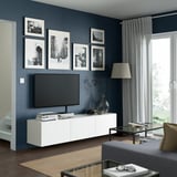 Modernes Wohnzimmer mit BESTÅ-TV-Bank, Flachbildfernseher, Couchtisch, Lampe und Fotos. Schlankes, minimalistisches Design. Die TV-Bank bietet viel Stauraum.
