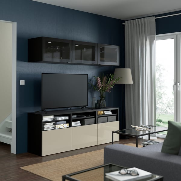 Modernes Wohnzimmer mit dunkelblauen Wänden, Flachbild-TV in der BESTÅ-Einheit, großen Fenstern, grauem Sofa und minimalistischer Einrichtung.