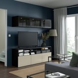 Modernes Wohnzimmer mit dunkelblauen Wänden, Flachbild-TV in der BESTÅ-Einheit, großen Fenstern, grauem Sofa und minimalistischer Einrichtung.