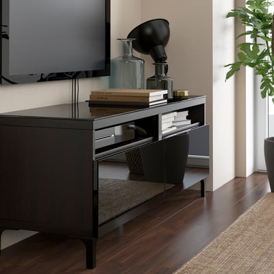 Fernsehschrank aus Glas mit Büchern, Vasen, Lampe, Fernseher, Pflanze, Teppich auf Holzböden.