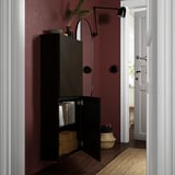 Schwarzer Wandschrank mit einer offenen Tür, der den Blick auf organisierte Akten und Kisten freigibt. Verstellbare Scharniere und vielseitige Aufbewahrungslösungen.