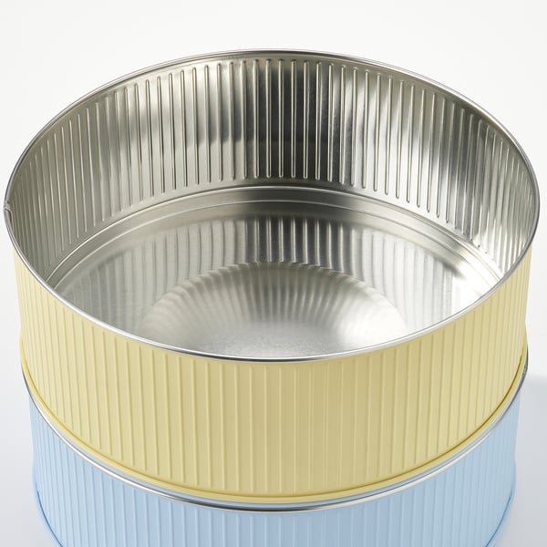 Zwei gestapelte Blechbehälter mit geripptem Design, einer blau, einer gelb.