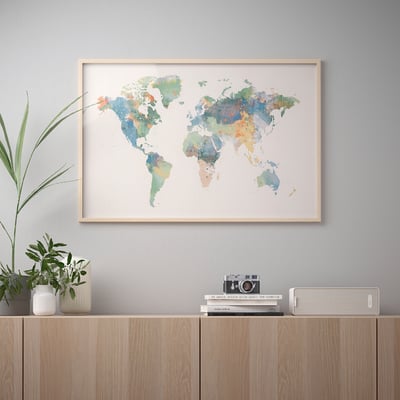 Gerahmte Weltkarten-Kunstwerke hängen an der Wand über einem Holzregal mit Pflanzen und Büchern.